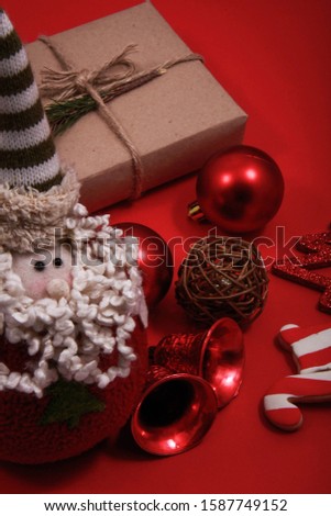 Santa clause doll near the other symbols of Christmas such as gift, ornaments, pine, pine leaves, etc.