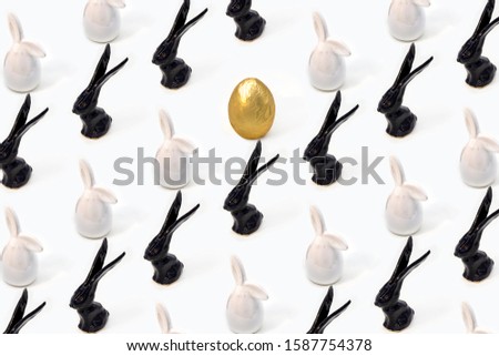 Trendy Easter pattern made of white and black rabbits hares toys and golden egg on white isometric background in minimal style. Easter bunny concept in minimal style.