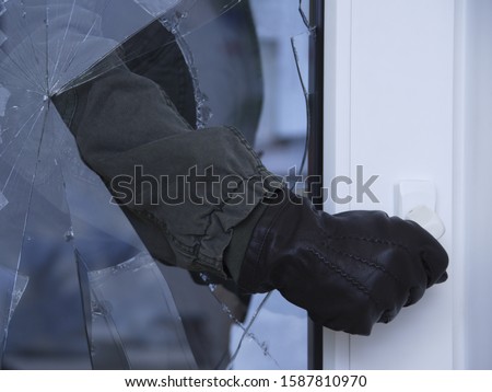 Burglar reaching through broken glass on door Royalty-Free Stock Photo #1587810970