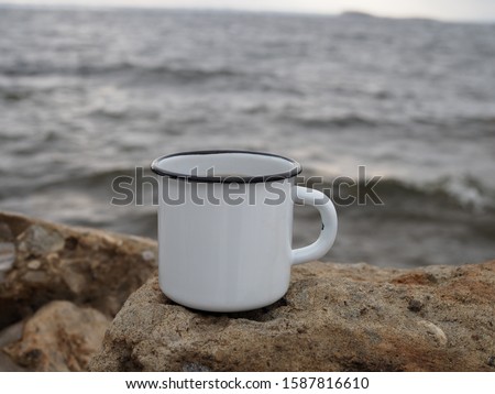 enamel white mug with coffee on a natural background of the river close-up. minimalism.