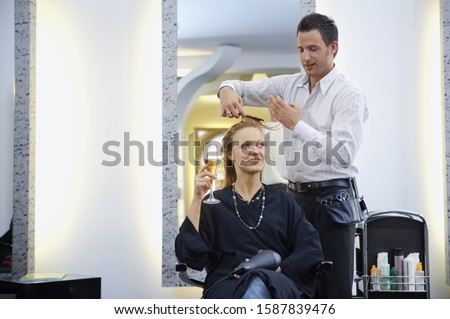 Male hair stylist cutting female client’s hair