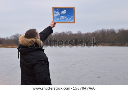 A man holds in his hand a picture of the summer sky and dreams of it