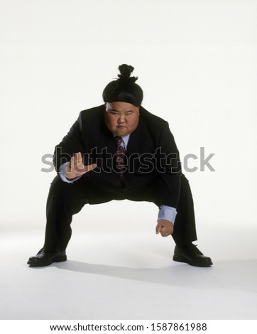 View of a sumo wrestler in a business suit squatting