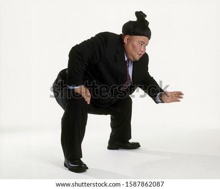 View of a sumo wrestler in a business suit squatting
