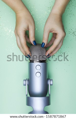 ASMR concept - woman hands skretching professional microphone in order to make stimulational sounds. Top view concept.