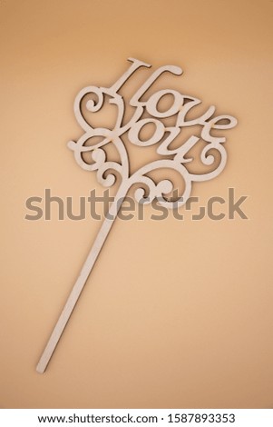 Openwork wooden inscription "I love you" on a beige background. Flat lay style.