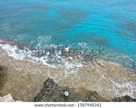 A man catches fish in the azure sea