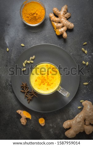 Cup of ayurvedic golden turmeric latte milk with curcuma powder and anise star on black. Top view. Healthy drink for improve immunity. Flat lay composition.