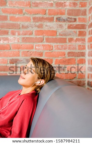 Teenage boy lying on a seat listening to music on mp3