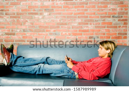 Teenage boy lying on a seat listening to music on mp3
