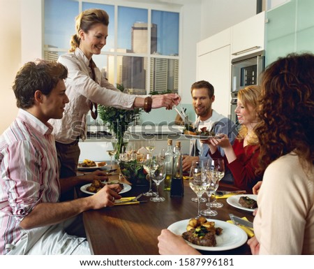 Woman serving food for friends at dinner table