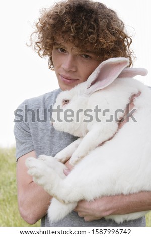 Young man holding rabbit outdoors