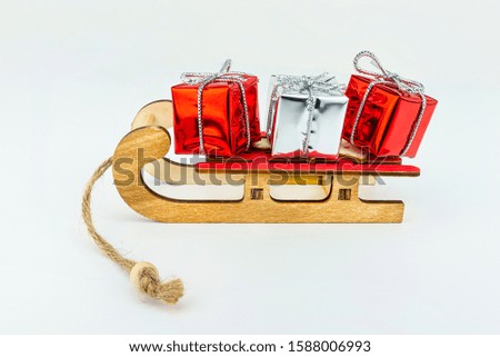 Macro picture of wooden sleds with a red seat with two red and one silver wrapped gift.