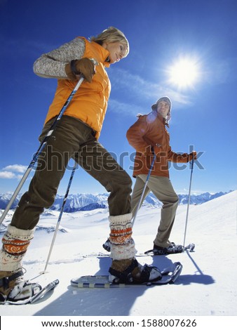 Low angle view of couple snowshoeing with ski poles