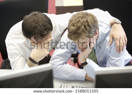 Businessman with arm around male coworker at desk