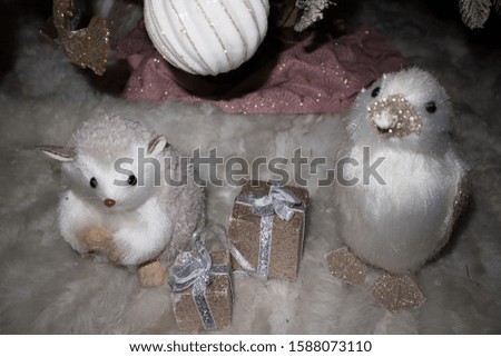 Focus on cute fake small animals, with two presents between them. Decorations under a christmas tree.