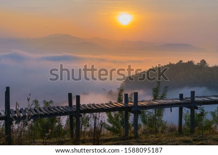 Silhouette the sunrise with a wooden skywalk, the fog, the beautiful sky and cloud at Phu Lam Duan Mountain, Pak Chom District, Loei Province, Thailand.