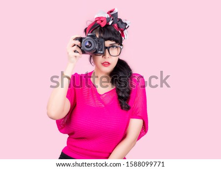 
Portrait of a beautiful asian young woman taking picture by digital camera on pink background.