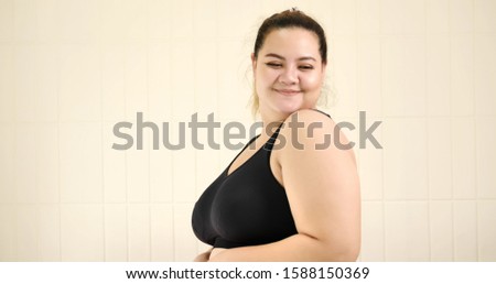 Happy chubby woman standing in the room.
