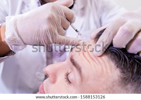 Caucasian man undergoing beauty spa botulinum neurotoxin Botox treatment for anti-aging, to smooth wrinkles as a cometic solution. Injecting forehead to relax muscles with a non-invasive procedure. Royalty-Free Stock Photo #1588153126