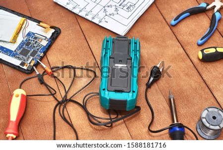 Disassembled tablet. Repair of modern broken electronic devices. Repair tools . Digital multimeter. Desktop appliances electronics. Schematic diagram of an electronic device. Screwdrivers.
