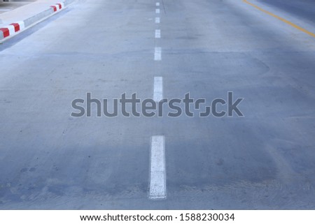Concrete road with a white markings lane.