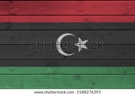 Libya flag depicted in bright paint colors on old wooden wall. Textured banner on rough background