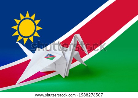 Namibia flag depicted on paper origami crane wing. Handmade arts concept