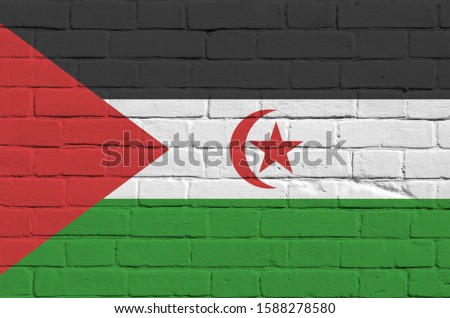 Western Sahara flag depicted in paint colors on old brick wall. Textured banner on big brick wall masonry background