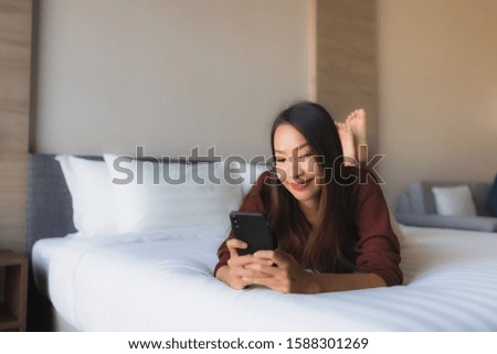 Portrait beautiful young asian women using mobile phone on bed in bedroom interior
