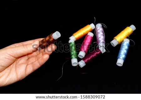 Female hands hold skeins of thread. Silk threads for embroidery. Skeins of yellow, blue, green pink, purple, brown and lilac. Black background. selective focus