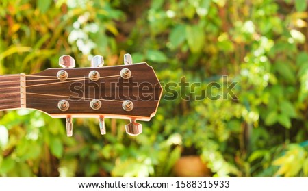 tip of  wooden guitar on outdoor background.