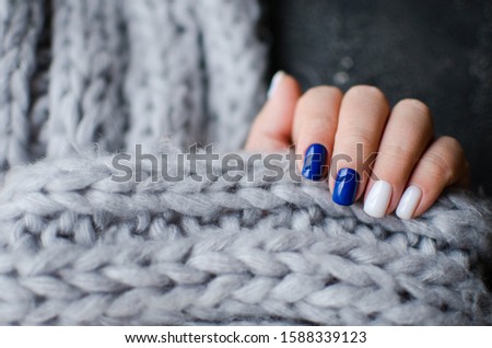 Women's hands with colorful pattern on the nails. Top view. Place for text. cozy winter style. classic blue manicure 2020