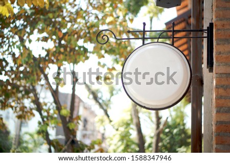 Photo blank white signboard mockup on street. Shop sign circle mockup on brick wall. Vintage signboard for restaurant, store, shop, cafe, jewelry store, etc. Close up view. Copy Space.