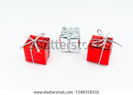 Macro picture of two red and one silver, shiny wrapped gift with bow, isolated on white background.
