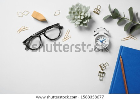 Glasses, alarm clock, eucalyptus and different stationery on white background, top view. Classic blue - color of the Year 2020