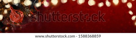Red Christmas banner of tree decorations and glowing lights on a blurred festive background.