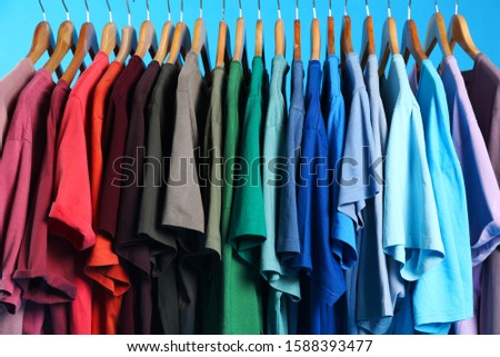 Colorful clothes on hangers against light blue background