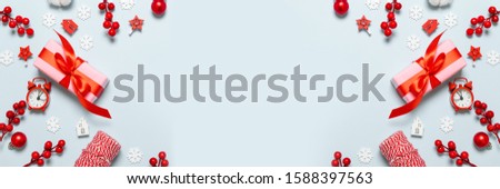 Creative frame with gifts boxes, clocks, white snowflakes decor, berries and houses on blue minimal background.