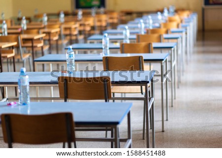 Exam examination room or hall set up ready for students to sit test. multiple desks tables and chairs. Education, school, student life concept.  Royalty-Free Stock Photo #1588451488