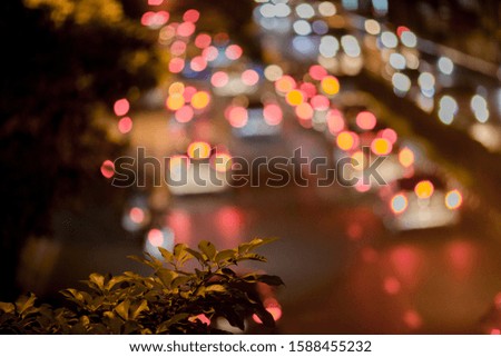 A blurry abstract background of the light of a car on a road that runs through a lot, hits the leaves Tree branches on the roadside, one of the artistic beauty in urban communities
