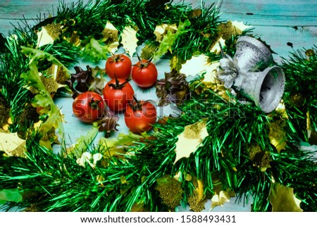 Christmas wreath with tomatoes and lettuce on turquoise  wooden background. Merry Christmas and Happy New year with tomato and lettuce for healthy food concept, greeting card, banner concept.