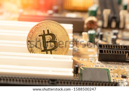 Bitcoin cryptocurrency, virtual money, blockchain technology concept. Golden coin on electronic mainboard.