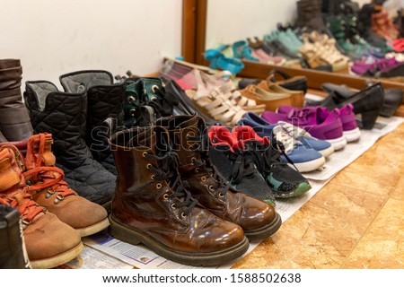 A lot of different used old shoes are laid out on the floor in the hallway. Storage Organization Concept. Royalty-Free Stock Photo #1588502638