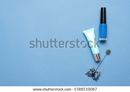 Nail polish and lip balm on blue background with copy space.