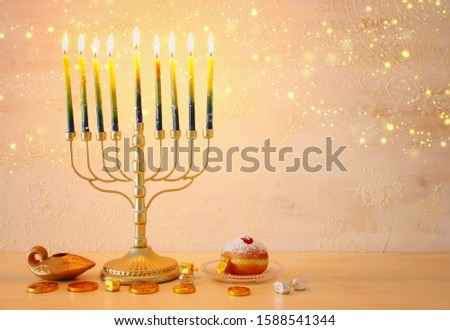 religion image of jewish holiday Hanukkah with menorah (traditional candelabra), spinning top and doughnut over wooden background