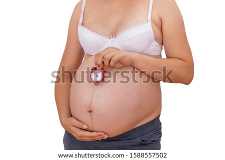 Pregnant woman holding alarm clock at belly isolated on white. Waiting baby concept.