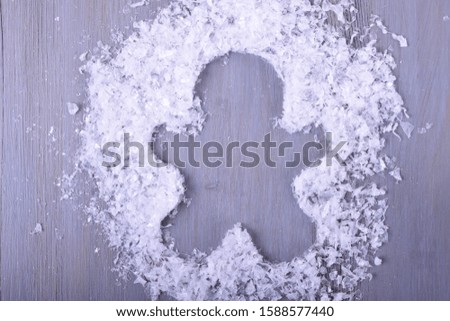 Gingerbread man silhouette in artificial snow on gray table