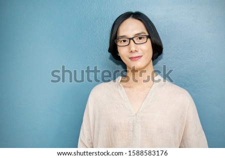 Portrait of attractive beautiful positive long hair asian man. Closeup portrait asian nerdy boy with copy space. Handsome nerd Japanese guy isolated on blue wall background.