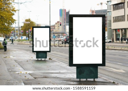 Two blank mockup of vertical street lightbox billboard on city background.